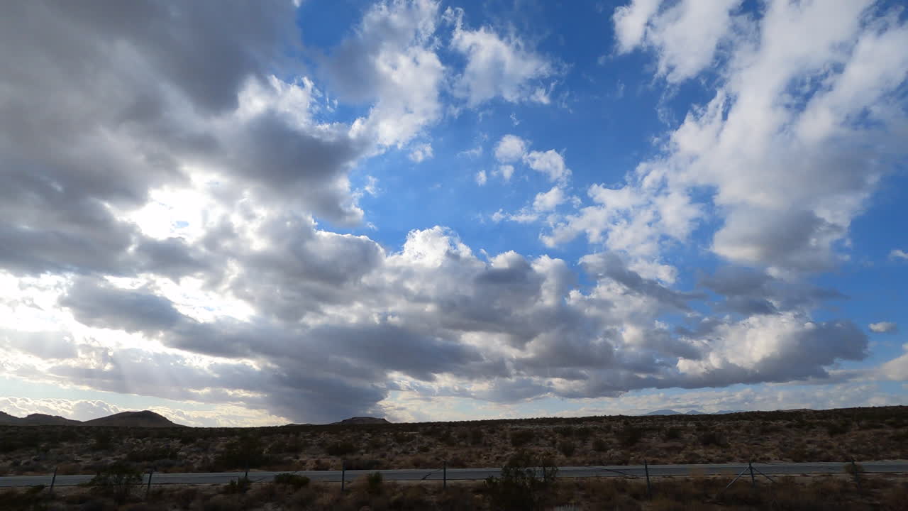 una vista de hiperlapso desde la ventana del lado del pasajero de un automóvil en el paisaje del desierto de mojave y el paisaje nuboso