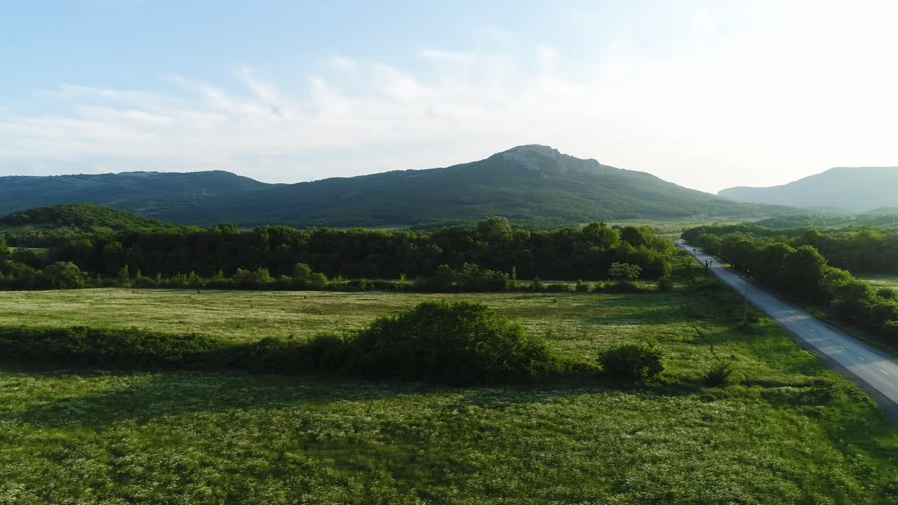 Scenic Country Road Through Lush Green Valley and Mountains