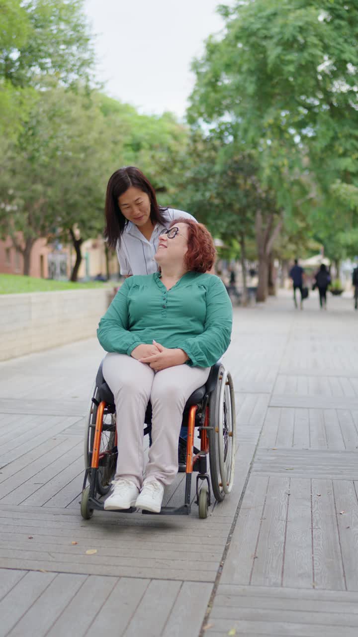 A woman in a wheelchair with a friend assisting her
