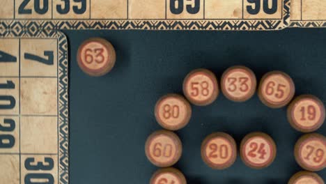 Filmische-Nahaufnahme,-Sanft-Rotierende-Zoom-Out-Aufnahme-Von-Oben-Eines-Bingo-Holzfässers-Im-Kreis,-Holzige-Figuren,-Alter-Zahlenhintergrund,-Vintage-Brettspiel,-Professionelle-Beleuchtung,-Zeitlupe-4k