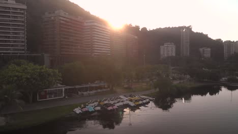 Movimiento-Giratorio-Aéreo-Del-Amanecer-Que-Muestra-Bicicletas-Acuáticas-En-La-Orilla-Del-Lago-De-La-Ciudad-En-Río-De-Janeiro-Que-Revela-La-Montaña-Corcovado-Detrás-De-La-Cordillera-Del-Barrio-Residencial