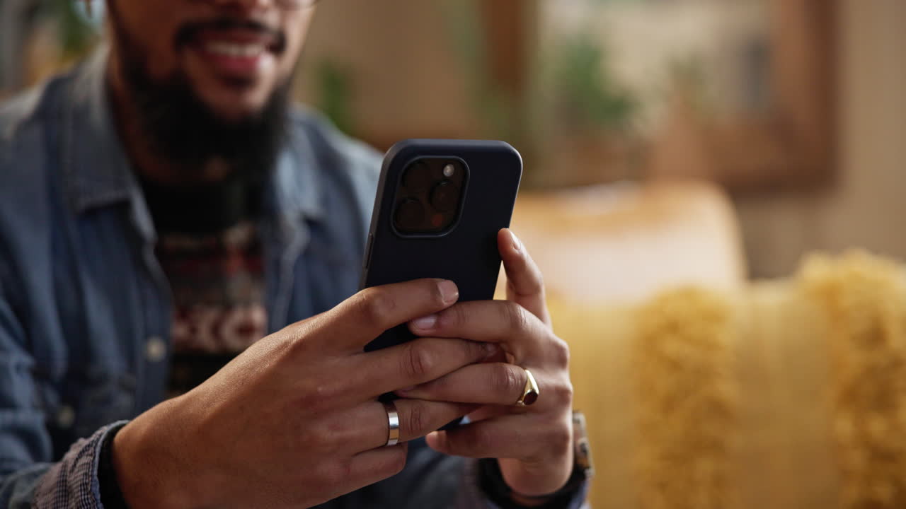 un hombre sentado en un sofá usando su teléfono inteligente