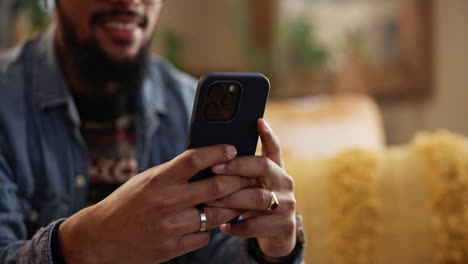 un hombre sentado en un sofá usando su teléfono inteligente
