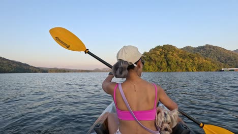 woman and dog kayaking on a serene lake