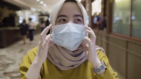 asian muslim women putting on medical face masks