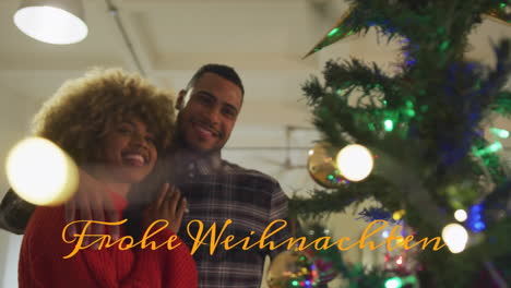 animation of frohe weihnachten text banner over biracial couple decorating christmas tree at home