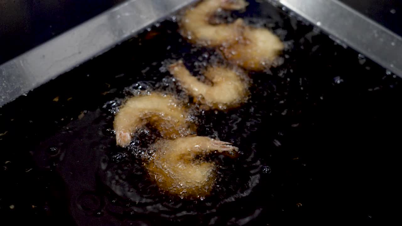 Crispy delights come to life as shrimp sizzle in hot oil at a bustling seaside eatery