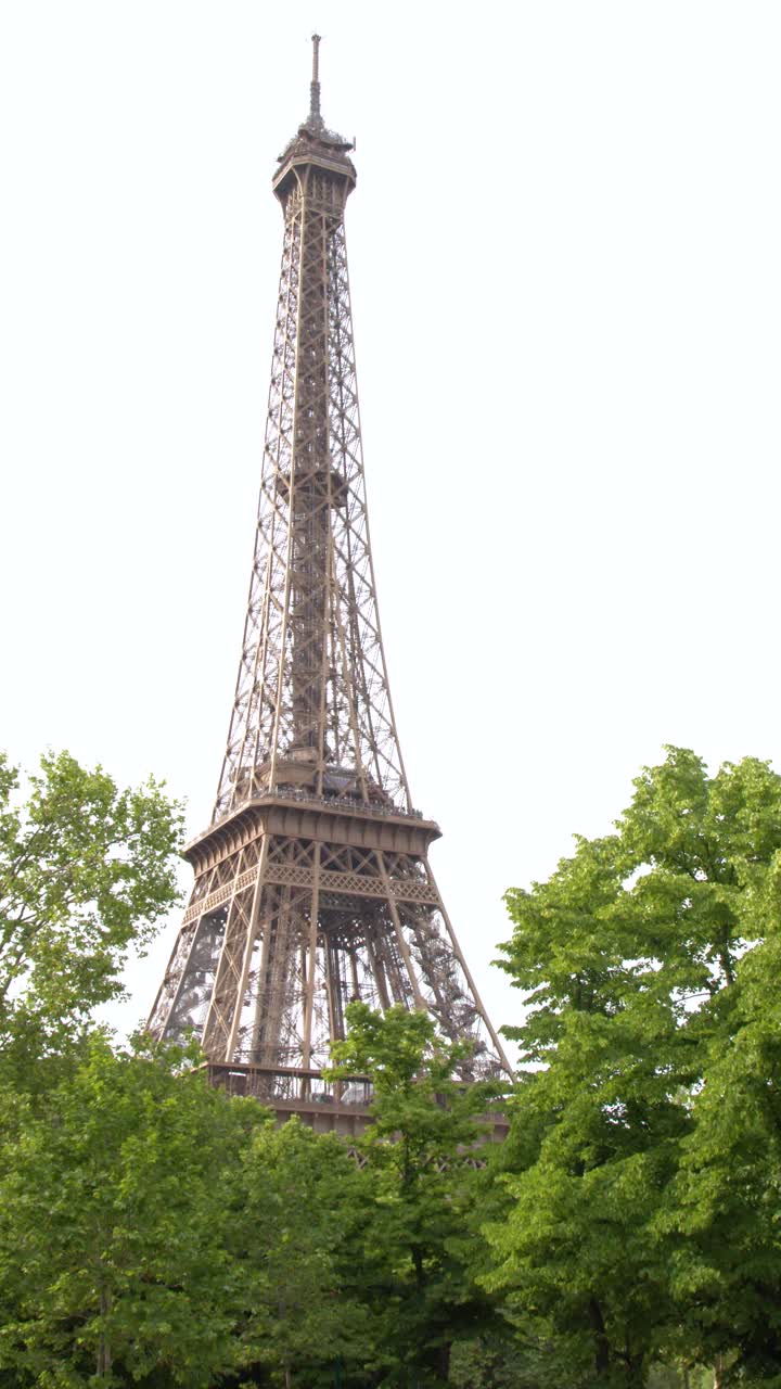 Vista dal basso del monumento storico in ferro dietro il fogliame verde a Parigi, Francia.