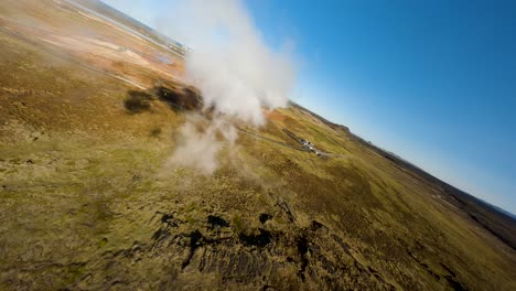 aerial fpv shot alongside a large cloud produced by a natural spring in iceland