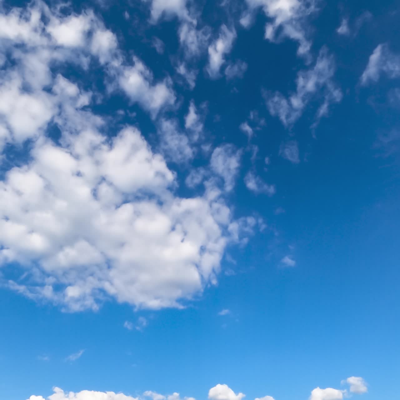 Light airy clouds moving along the blue sky. Beautiful white fluffy clouds against bright sky. Timelapse