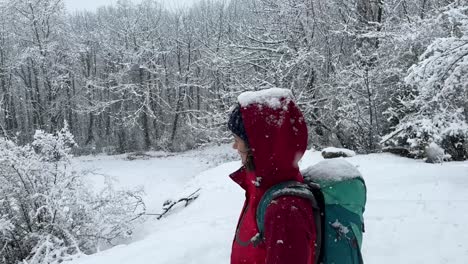 Eine-Frau-Trägt-Eine-Jacke-Beim-Wandern-Im-Schnee-Und-Geht-Bergab-Im-Hyrkanischen-Wald,-Wunderbare-Schwere-Schneelandschaft,-Zugefrorener-See,-Bäume-Bedeckt-Von-Starkem-Schneefall,-Wintersport-Abenteuer,-Ländliches-Dorf,-Land,-Iran