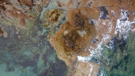 aerial top-down forward over waves breaking on rocky coast of saint-malo in brittany, france