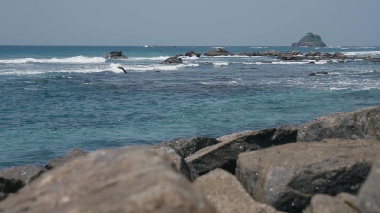 Gelombang laut biru yang menghantam dan memercik di pantai berbatu di Weligama, Sri Lanka.