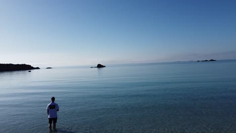 Hombre-De-Pie-En-El-Agua-Clara-De-Una-Bahía-En-Córcega