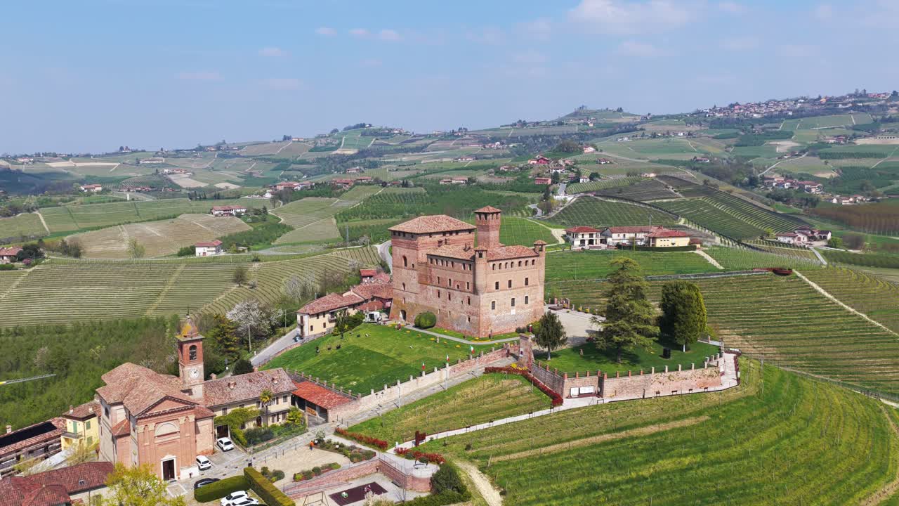 Orbiting aerial shot of Grinzane Cavour castle surrounded by lush vineyards and rolling hills, showcasing the iconic medieval architecture and the picturesque Langhe countryside