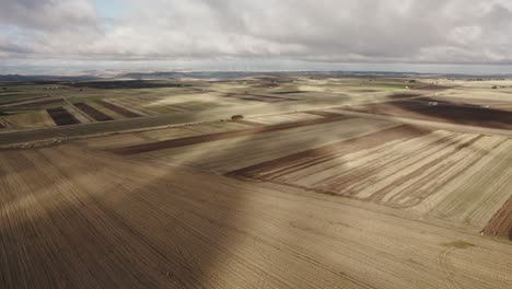 Drone-flying-sideways-and-downwards-over-farmfields-with-fast-moving-clouds-making-patterns-in-the-fields-in-Italy-in-4k