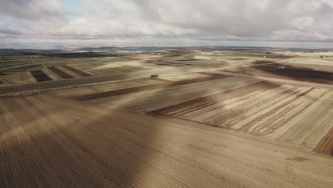 drone flying sideways and downwards over farmfields with fast moving clouds making patterns in the fields in italy in 4k