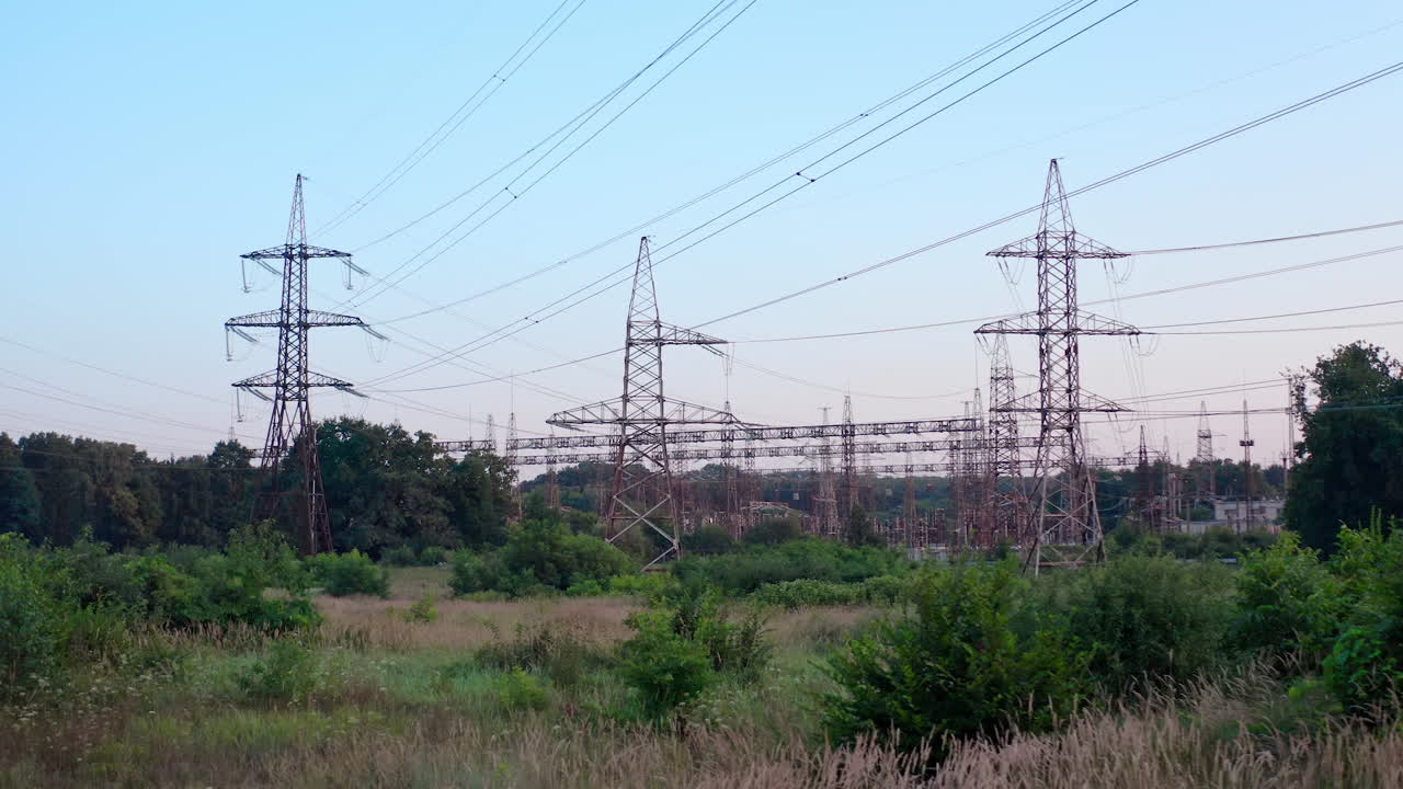 Transmission lines in nature. High voltage electric towers on blue sky background. Tall steel pylons and wires distribute electricity