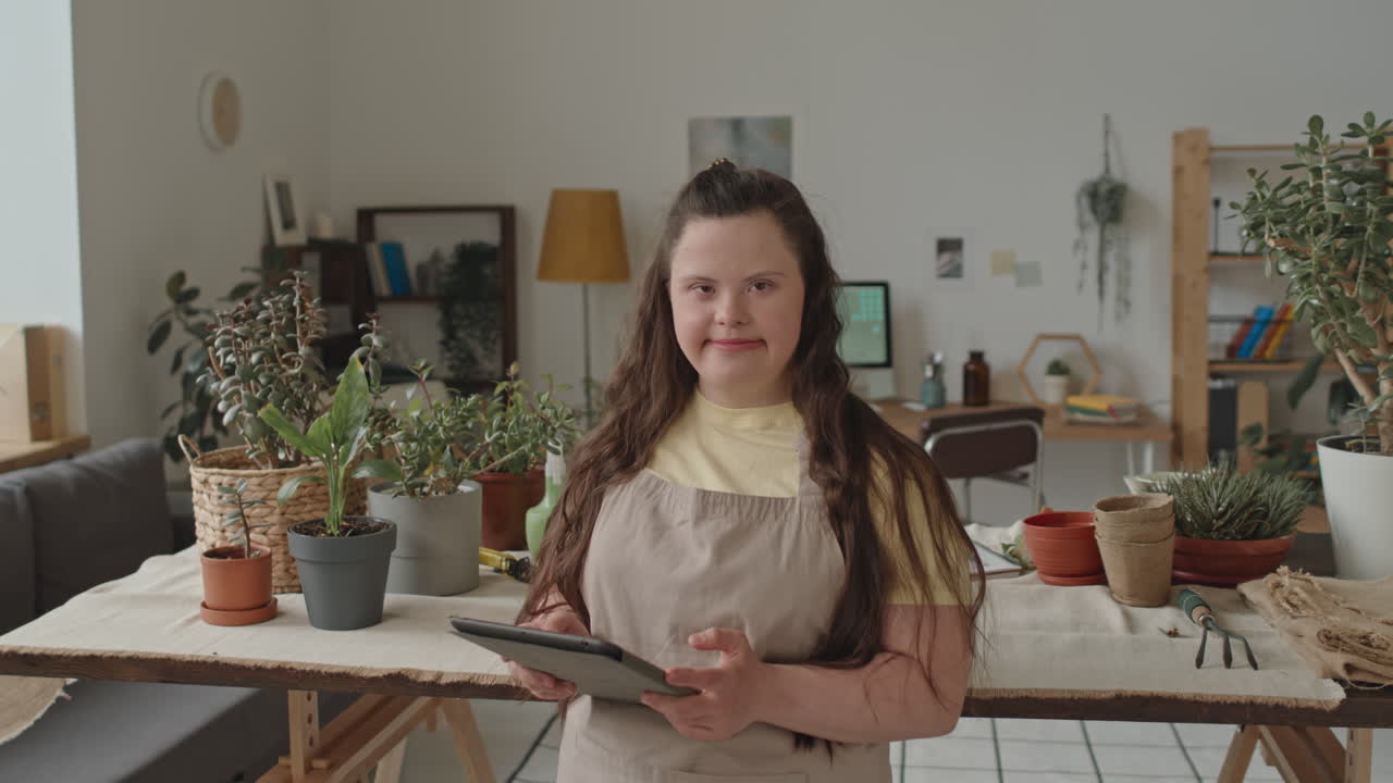 Woman with Down Syndrome Holding Tablet Surrounded by Plants