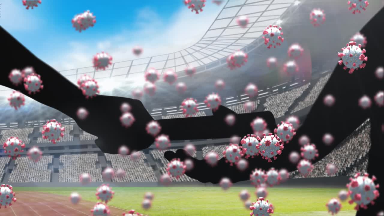 코로나19 세포가 스포츠 경기장을 향해 지 ⁇ 이를 전달하는 손의 실루 ⁇ 에 대해 떠다니고 있습니다.