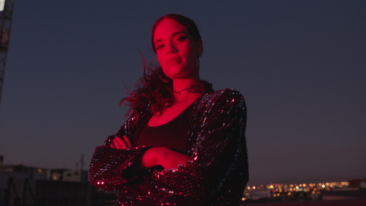 retrato de una mujer hermosa posando con los brazos cruzados por la noche buscando confianza con la luz roja en la ciudad