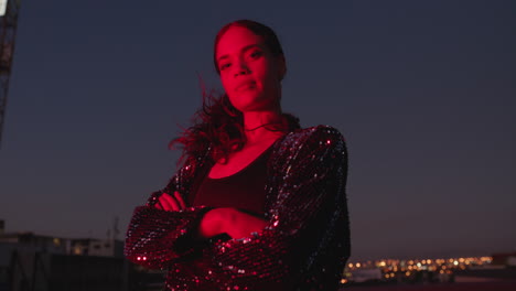 Retrato-Hermosa-Mujer-Posando-Con-Los-Brazos-Cruzados-Por-La-Noche-Luciendo-Confiada-Con-Luz-Roja-En-La-Ciudad