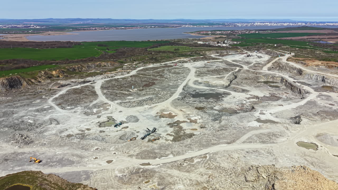 Granitbrud med maskineri og landskabsformationer nær et vandområde i dagslys