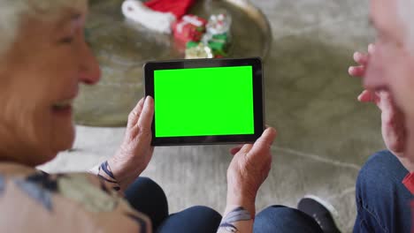 pareja caucásica mayor sonriente en sombreros de santa tablet videollamada de navidad, con pantalla verde