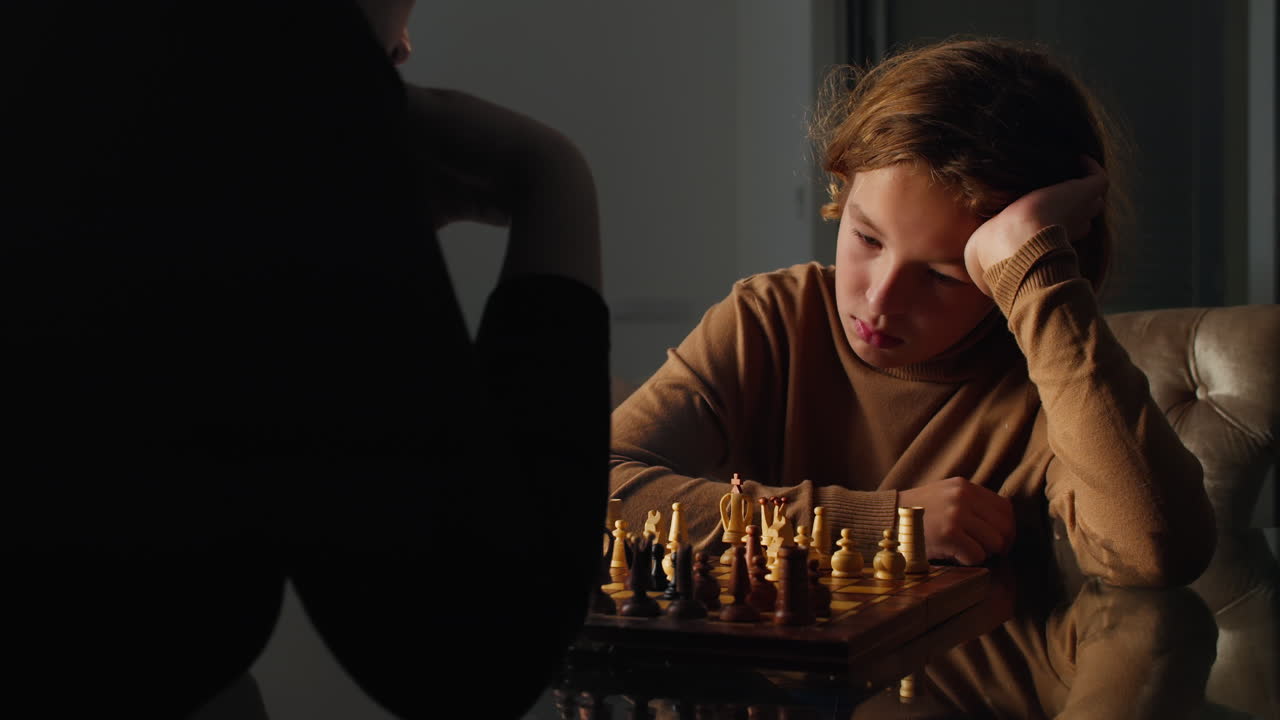Young boy intently studies the chessboard and makes a move