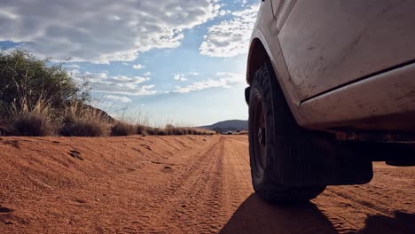 low angle pov: white vehicle drives on golden sandy desert road