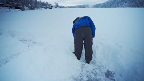 man in winter clothes making pathway using shovel after snowstorm at trondheim, norway