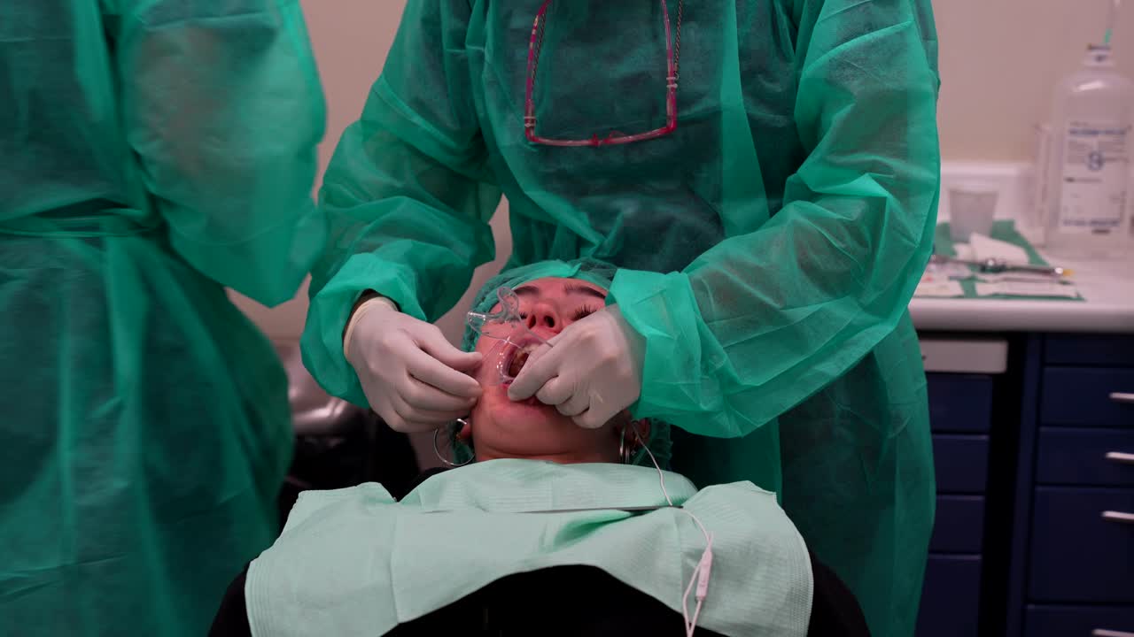 asistente de dentista colocando el retractor de mejillas mientras el odontólogo prepara la cámara
