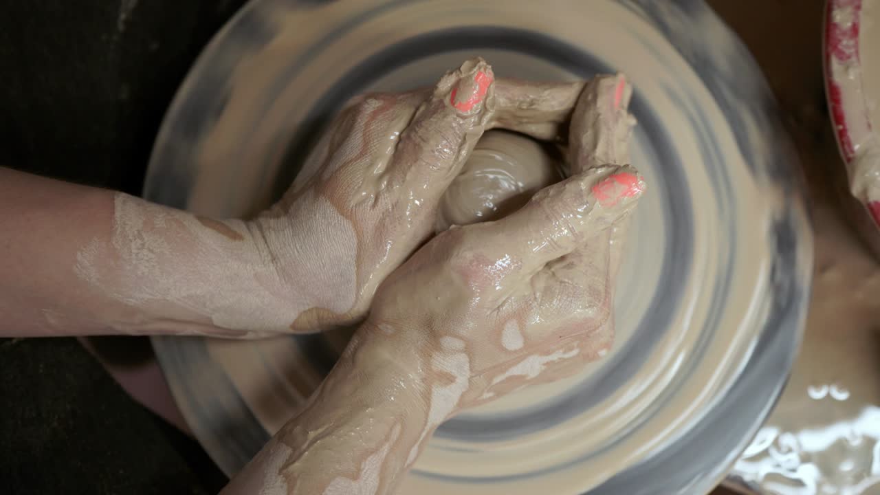 una mujer alfarera hace platos de arcilla. una mujer hace una jarra en la rueda de un alfarero