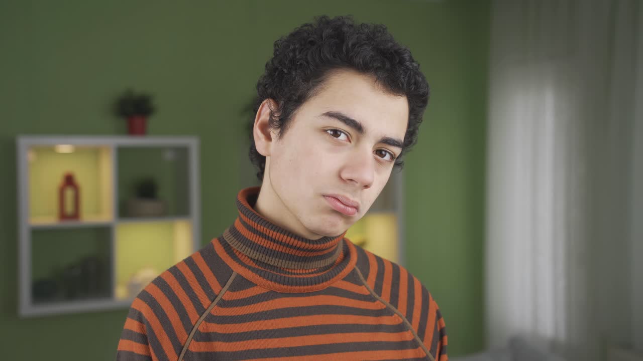 joven en casa mirando a la cámara con tristeza y gran infelicidad.