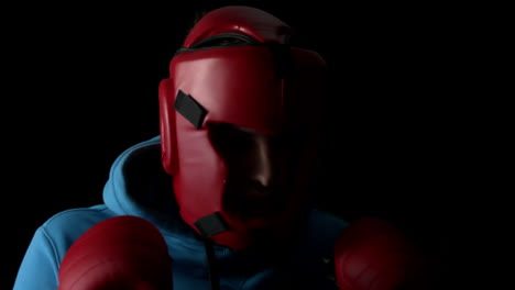 sporty young man boxing on black background