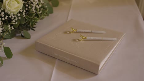 wedding guestbook with pens and white floral arrangement – elegant reception table detail