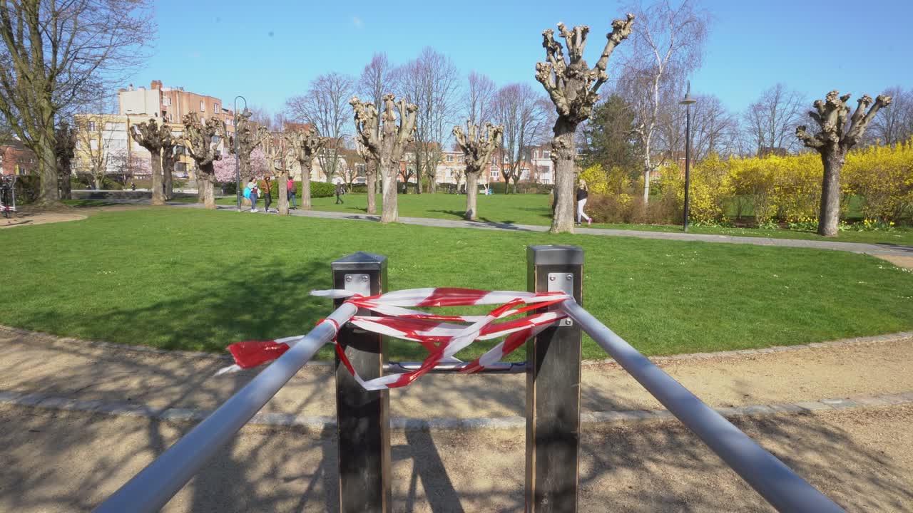 Wide symmetric shot of people walking by while fitness material can't be used because of Coronavirus.