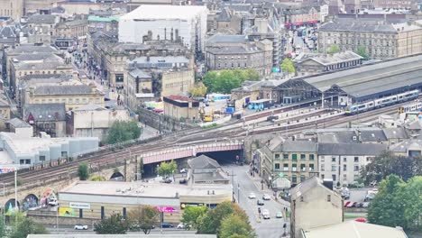 bustling train transit station in huddersfield as cars drive below, aerial overview