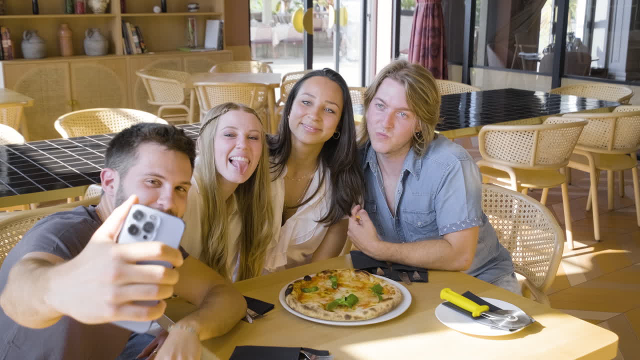 grupo de amigos tomando una foto selfie mientras comen pizza en un restaurante