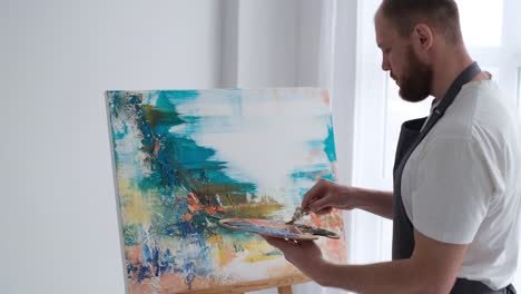 young talented artist working on abstract painting uses paint brush to create picture working in