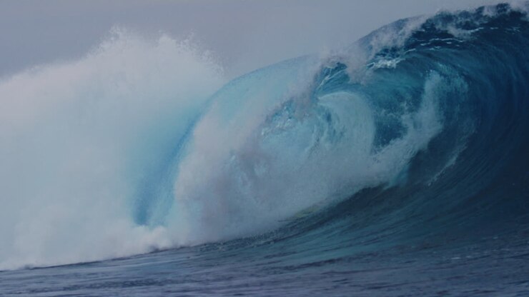 Slow motion sideview of surfer bailing off of board as it gets tossed over the falls at Cloudbreak Fiji