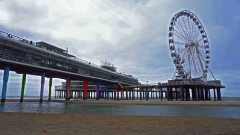 view of the ferris wheel and the pier from the beach in scheveningen, netherlands