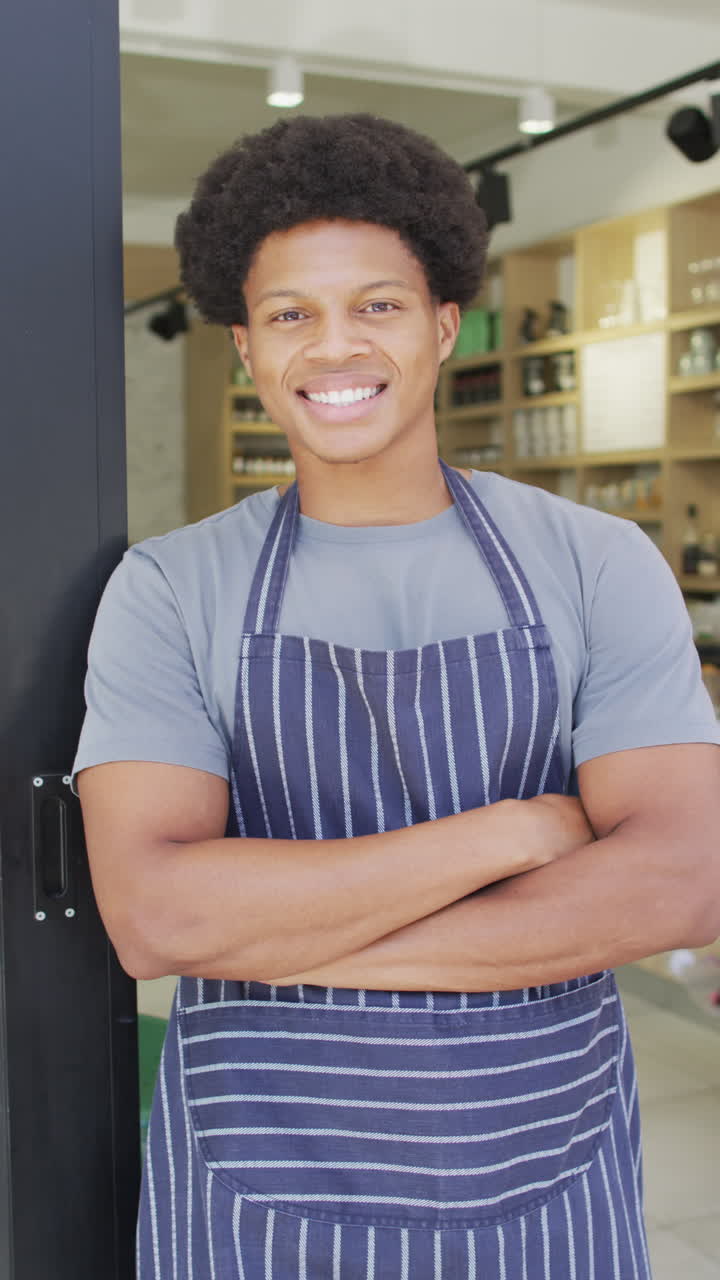 Vertikales Video eines lächelnden afroamerikanischen Baristas mit Schürze im Café