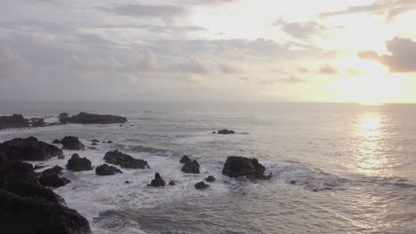 waves lightly crashing on rocks at sunset