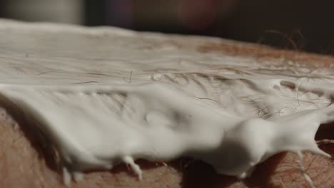macro shot of safety razor shaving hairy skin with shaving cream