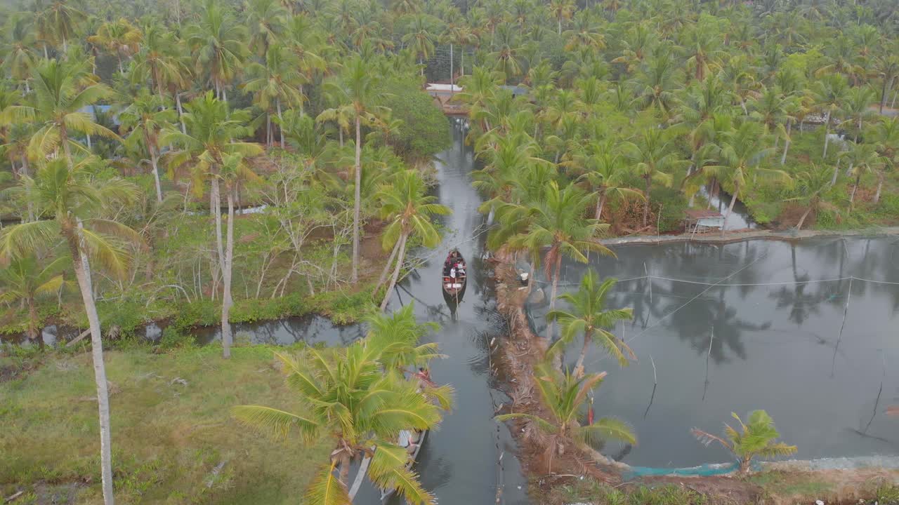 Veduta aerea di barche tradizionali che galleggiano su stretti canali e corsi d'acqua tra le palme dell'isola di Munroe, India.