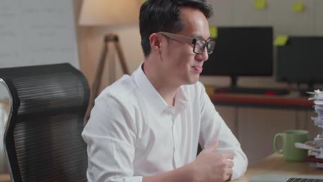 close up of asian man having video call on laptop while working with documents at the office