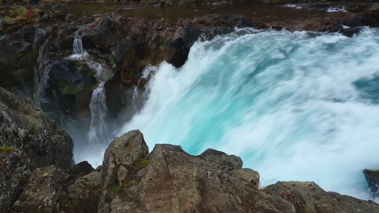 impresionante cascada con agua de glaciar azul que cae en cascada a través de rocas volcánicas
