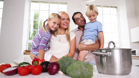 niños en los brazos de sus padres en la cocina