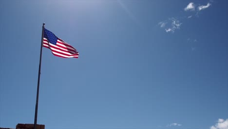 american flag against a blue sky blowing in the wind